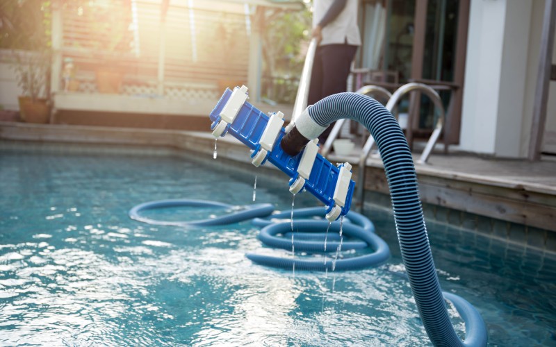 man-cleaning-swimming pool with vacuum tube cleaner