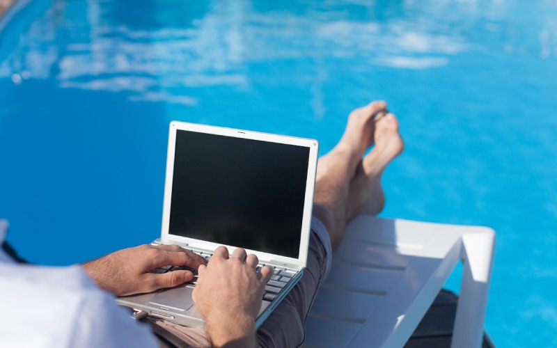 man using laptop near swimming pool