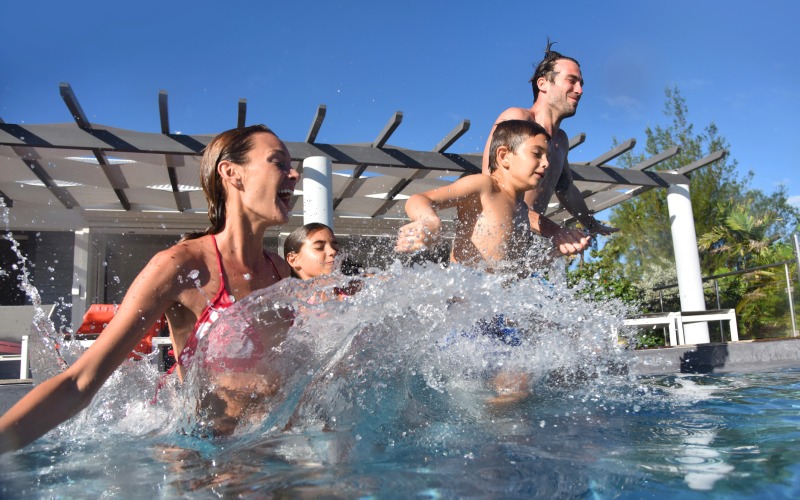 family jumping into l swimming pool