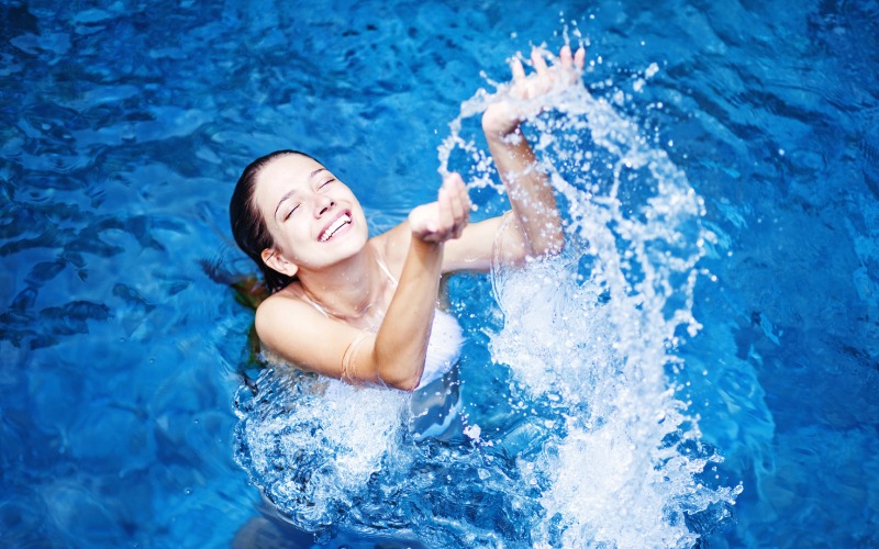 young beautiful woman splashing water in swimming pool